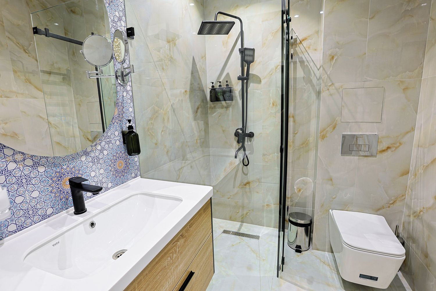 A modern bathroom with a white sink, a glass shower enclosure, and a toilet.