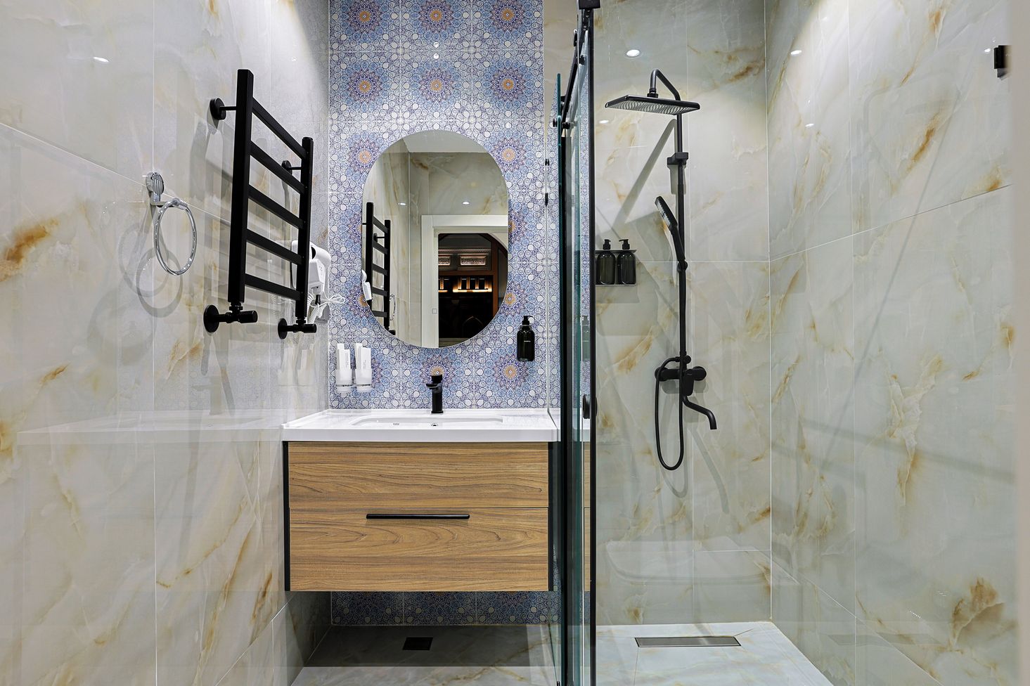 Une salle de bain moderne avec un meuble-lavabo en marbre, une douche à parois de verre et un mur décoratif recouvert de carreaux.