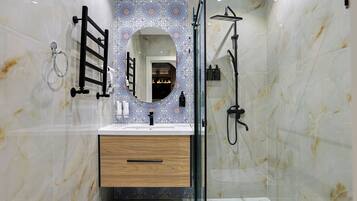 Une salle de bain moderne avec un meuble-lavabo en marbre, une douche à parois de verre et un mur décoratif recouvert de carreaux.
