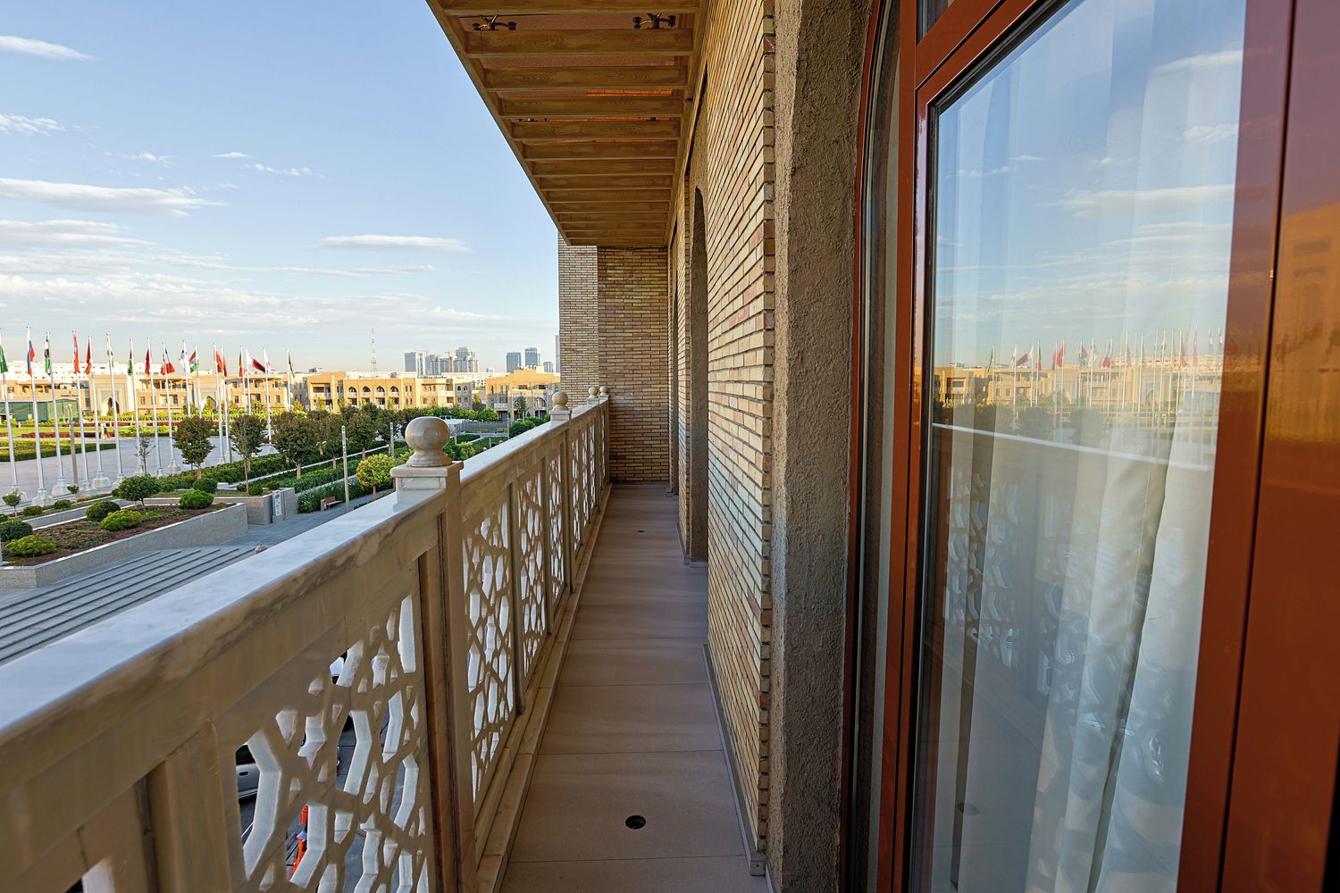 A balcony with a view of a cityscape, a wooden ceiling, and a glass door.