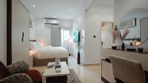 Una habitación de hotel moderna con cama, escritorio, silla, espejo y televisión.