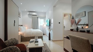 Une chambre d’hôtel moderne équipée d’un lit, d’un bureau, d’une chaise, d’un miroir et d’une télévision.