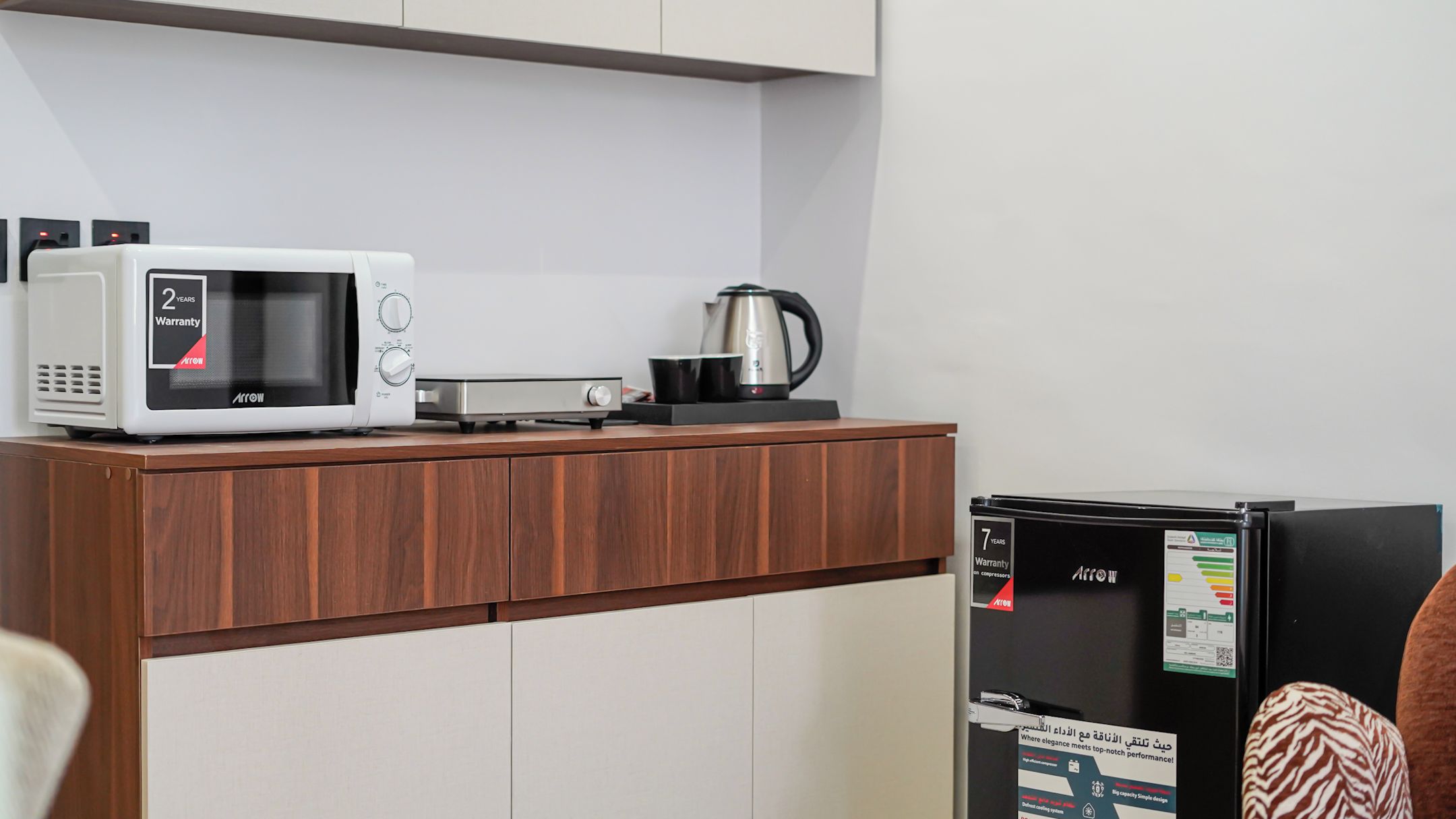 Una kitchenette equipada con microondas, hervidor y refrigerador.