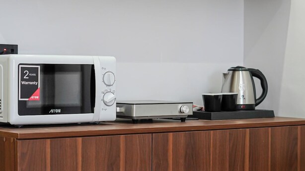 Una cocina con microondas, hervidor y tostadora sobre una encimera de madera.