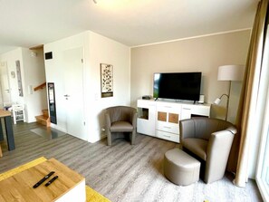 A modern living room with a flat-screen TV, two leather armchairs, a sofa, a wooden coffee table, and a white entertainment unit. - No. 17, Dike Warden (Wangerland)