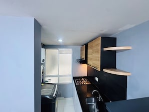 A compact kitchen with a gas stove, a sink, and wooden cabinets.