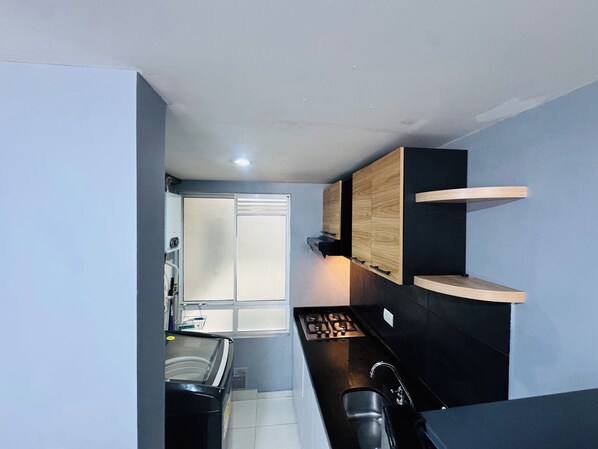 A compact kitchen with a gas stove, a sink, and wooden cabinets.