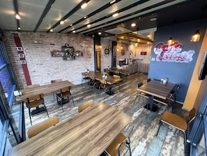 L'intérieur d'un café, avec des murs en briques, des tables en bois et des luminaires suspendus.