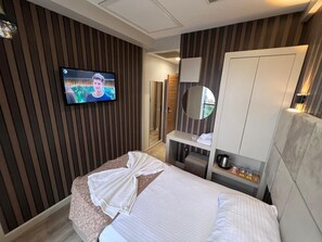 Une chambre d’hôtel comprenant un lit, un téléviseur fixé au mur, un miroir et une armoire.