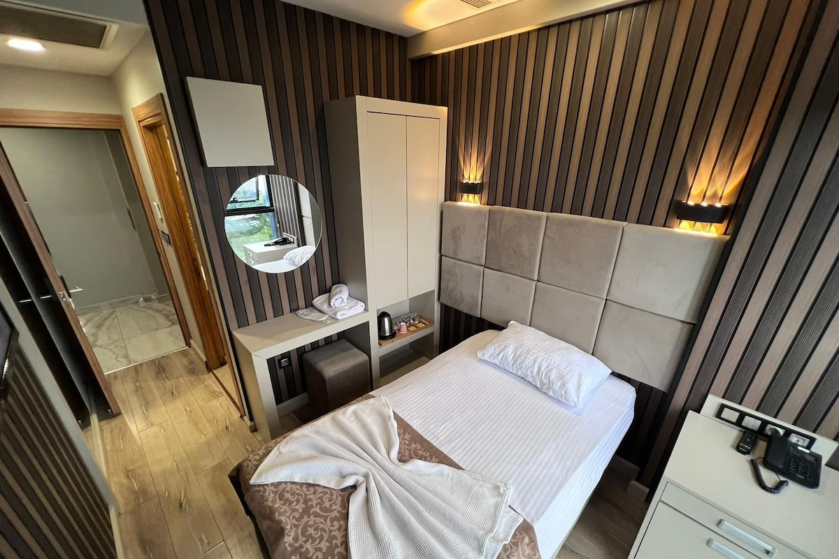 Une chambre d’hôtel comprenant un lit, une table de chevet, un miroir, une armoire et un bureau avec un téléphone.
