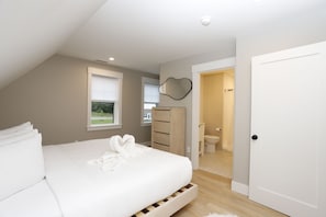 Ein Schlafzimmer mit einem Bett, einem Schminktisch, einem Spiegel und einer Tür zu einem Badezimmer.