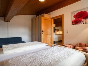 A bedroom with a bed, a wardrobe, a blue sofa, and a red flower painting on the wall. - Gästehaus Steger incl. Sommercard by Interhome (Zell am See)