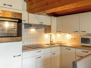 Une cuisine moderne avec des meubles blancs, des appareils en acier inoxydable et un plafond en bois.