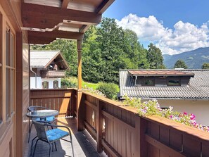 A wooden balcony with a table and chairs, overlooking a mountain landscape. - Gästehaus Steger incl. Sommercard by Interhome (Zell am See)