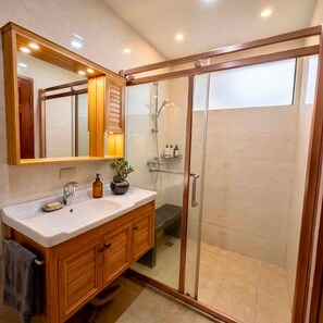 A bathroom with a wooden vanity, a glass shower enclosure, and a large mirror. - Cozy Stay for Couple (Parañaque)