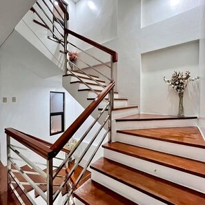 A modern staircase with wooden steps and metal railings, leading to an upper floor. - Cozy Stay for Couple (Parañaque)