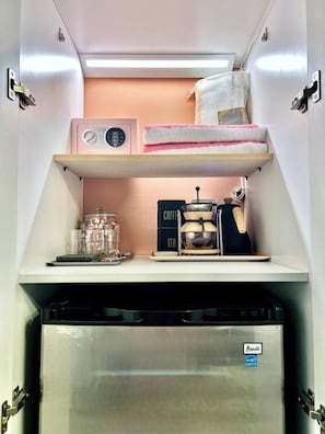 Une petite cuisine équipée d’une machine à café, d’une bouilloire et d’un petit réfrigérateur.
