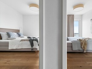 Ein modernes Schlafzimmer mit einem Bett, Nachttischen und einem Fenster mit Vorhängen.