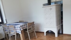 Un'area pranzo con un tavolo apparecchiato per due, un armadietto bianco con cassetti e un termosifone.