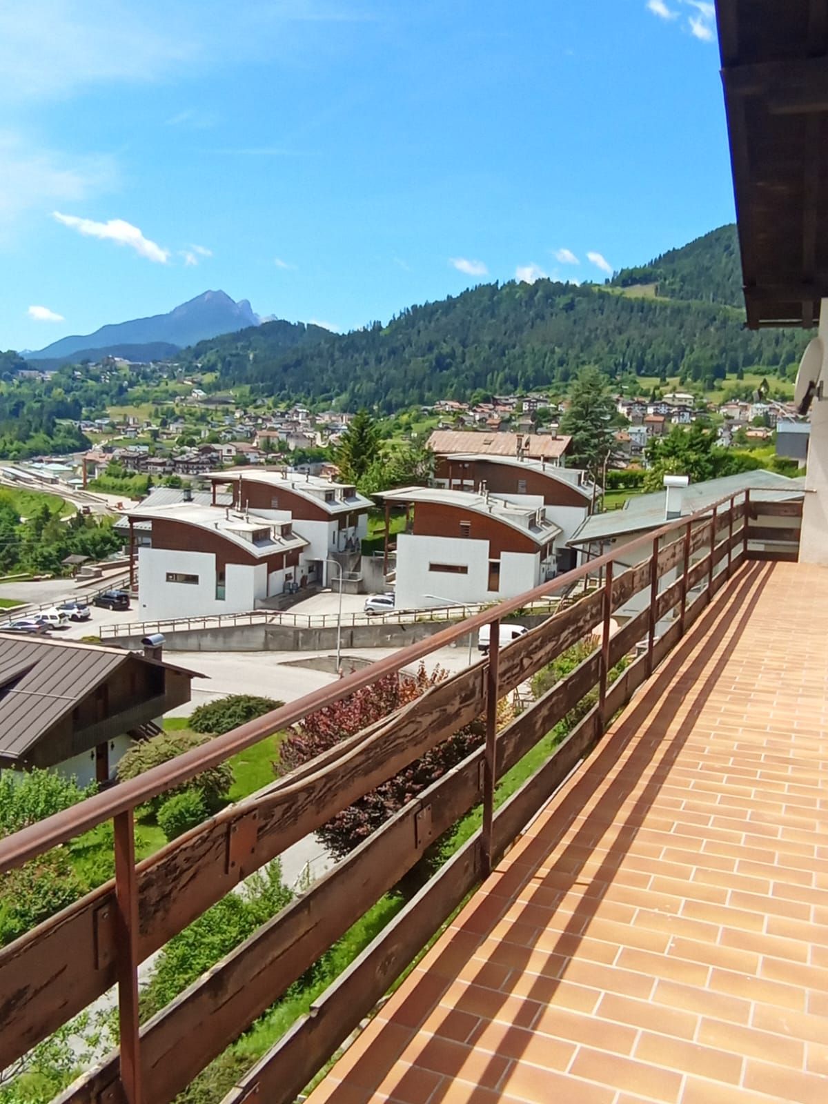 A balcony with a view of a residential area, a mountain, and a clear sky.