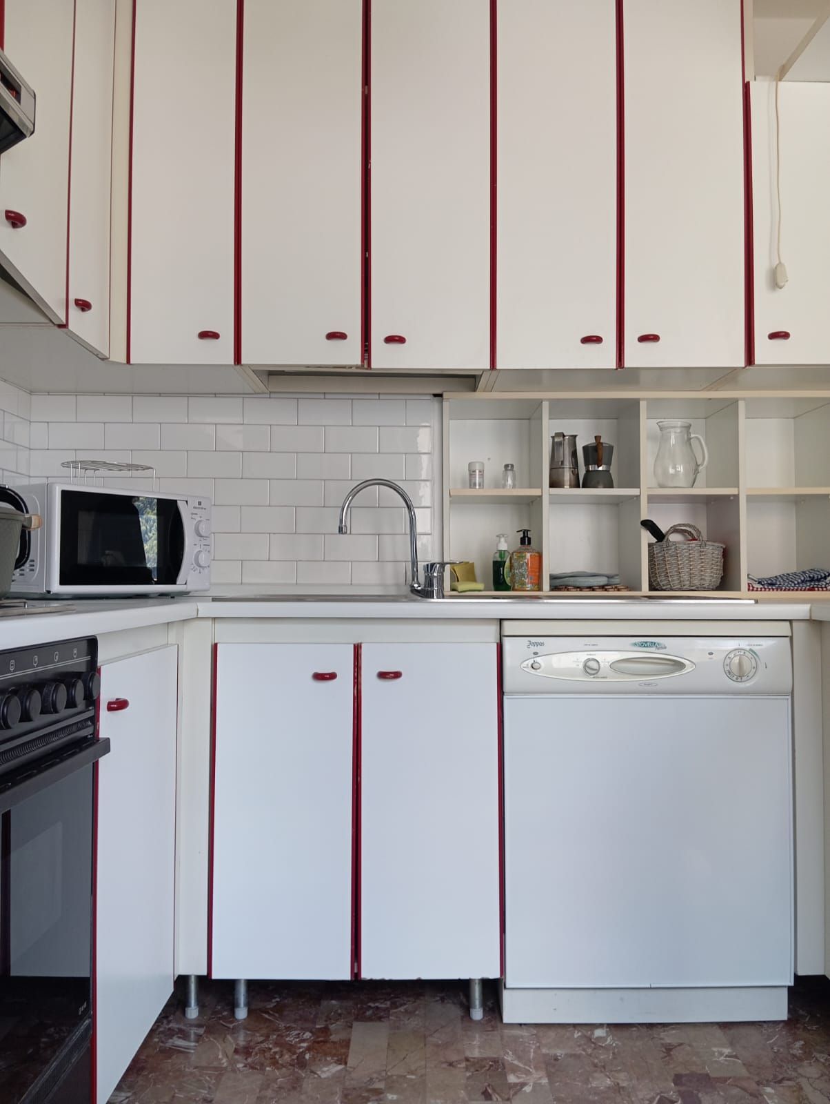 Una cocina con armarios blancos, un microondas, un fregadero y un lavavajillas.