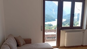 Un soggiorno con un divano componibile, un tavolino in legno e una grande finestra vista su un paesaggio montuoso.