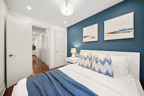A bedroom with a bed, a nightstand, a lamp, and two wall-mounted paintings. - Modern Queen West Escape Sleeps 6 with Parking (Toronto)