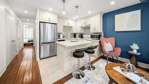Una cocina moderna con armarios blancos, electrodomésticos de acero inoxidable y una isla central con taburetes de bar.
