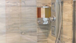 Un baño con cabina de ducha, panel de control y pared de azulejos.