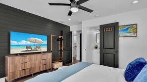A bedroom with a bed, a TV on a wooden cabinet, a ceiling fan, and a door leading to a bathroom. - **SUNSET ON FOGARTY @ MIDTOWN** Newly Renovated Home & Pool + Last Key White Glo (Key West)