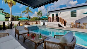 Un espace aménagé au bord de la piscine, comprenant un jacuzzi, une terrasse en bois et du mobilier d’extérieur.