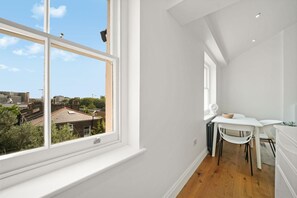 A narrow hallway with a window offering a view of buildings and trees. - Between Camden & Kings Cross. Above the Ordinary - Pass the Keys (London)