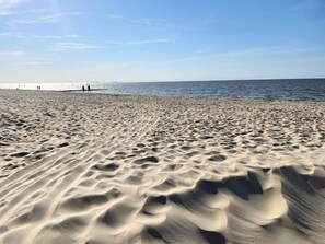 Una playa con ondulantes dibujos en la arena y cielo despejado.