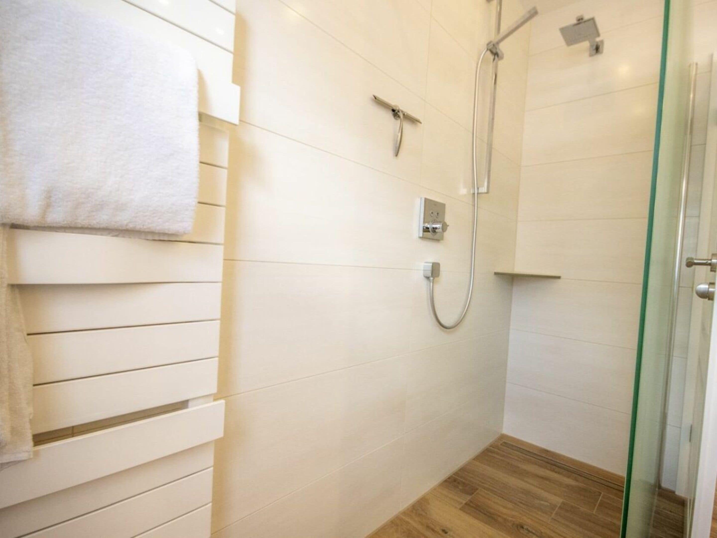 Een badkamer met een douche, een handdoekhouder en een glazen deur.