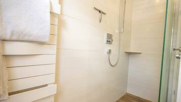 Een badkamer met een douche, een handdoekhouder en een glazen deur.