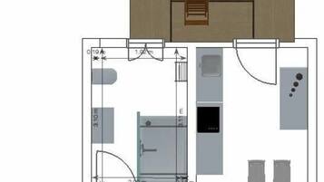 A floor plan of a hotel room with a bed, a bathroom, a kitchenette, and a dining area.