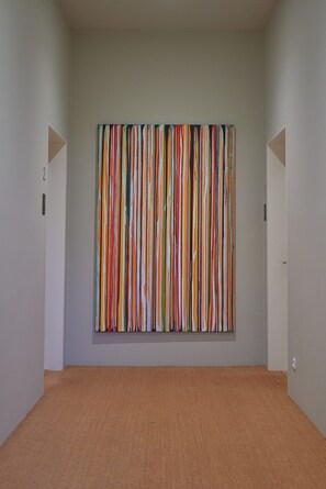 Ein Zimmer mit einem großen, abstrakten Gemälde an der Wand, Teppichboden und zwei Türen.