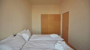 Quarto de hotel com cama, almofadas, guarda-roupa de madeira e porta.