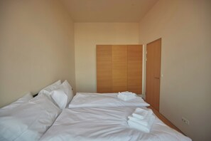 Quarto de hotel com cama, almofadas, guarda-roupa de madeira e porta.