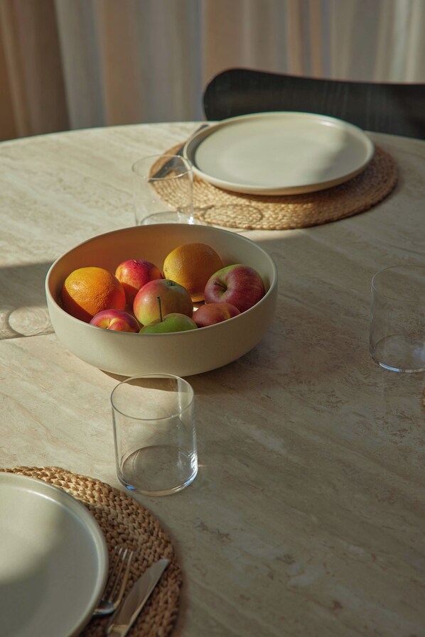 A table set with a bowl of fruit, a glass, and a plate.