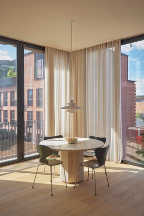 A modern dining area with a round table, chairs, and a pendant light.