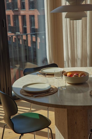 A dining table with plates, glasses, and a bowl of fruit, set for a meal.
