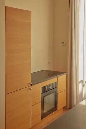 Cozinha moderna com armários de madeira, lava-louças de aço inoxidável e janela com cortinas.