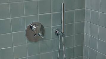 A shower with a handheld showerhead and a wall-mounted control valve.