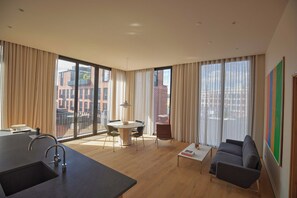 A modern living room with a dining area, large windows, and a view of buildings.