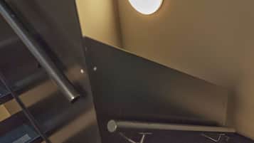 Uma escadaria com corrimãos de metal e um candelabro circular na parede.