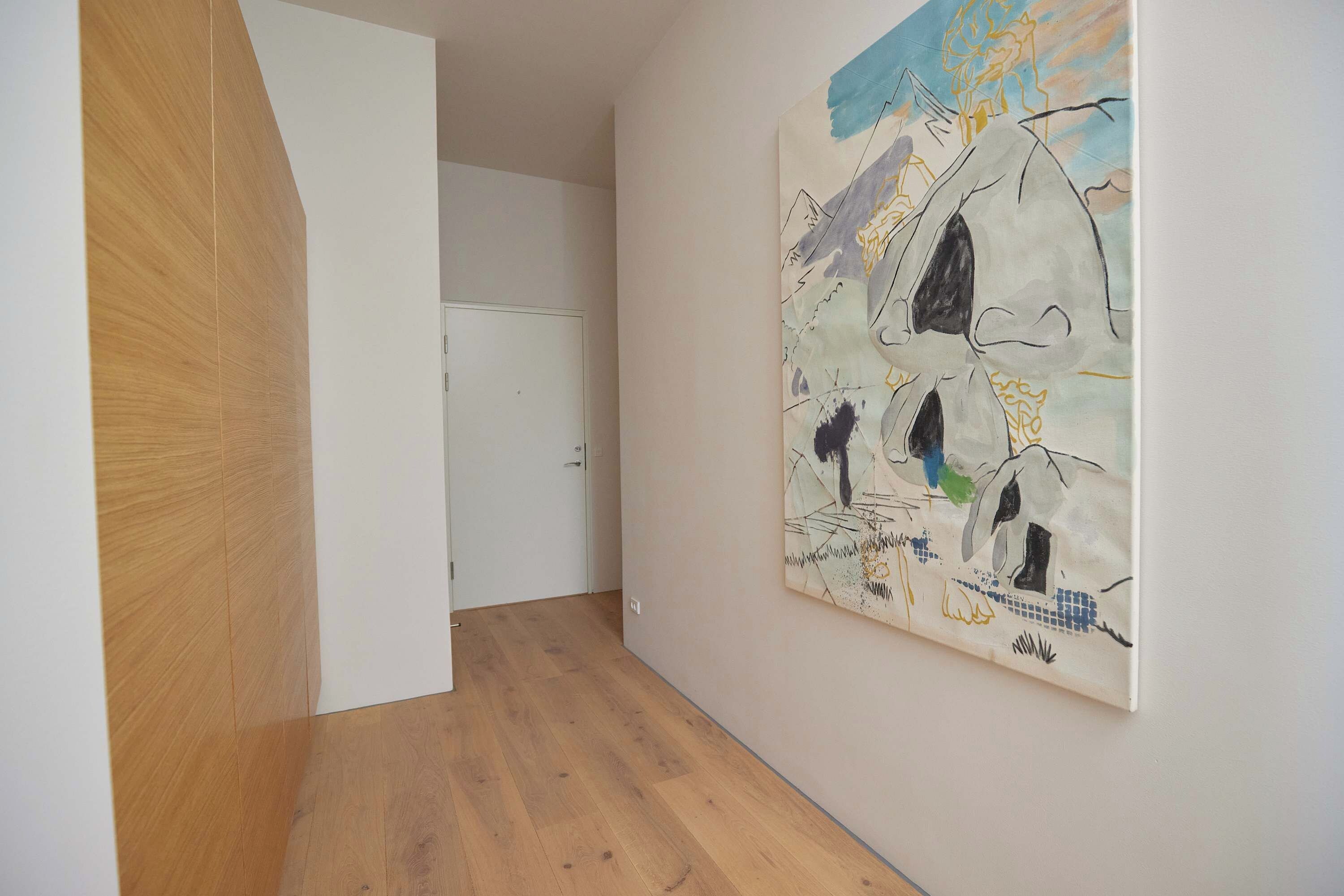 A hallway with a wooden floor, a white door, and a large abstract painting on the wall.