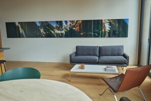 Un salon moderne avec un canapé gris, une table basse et un grand tableau abstrait accroché au mur.