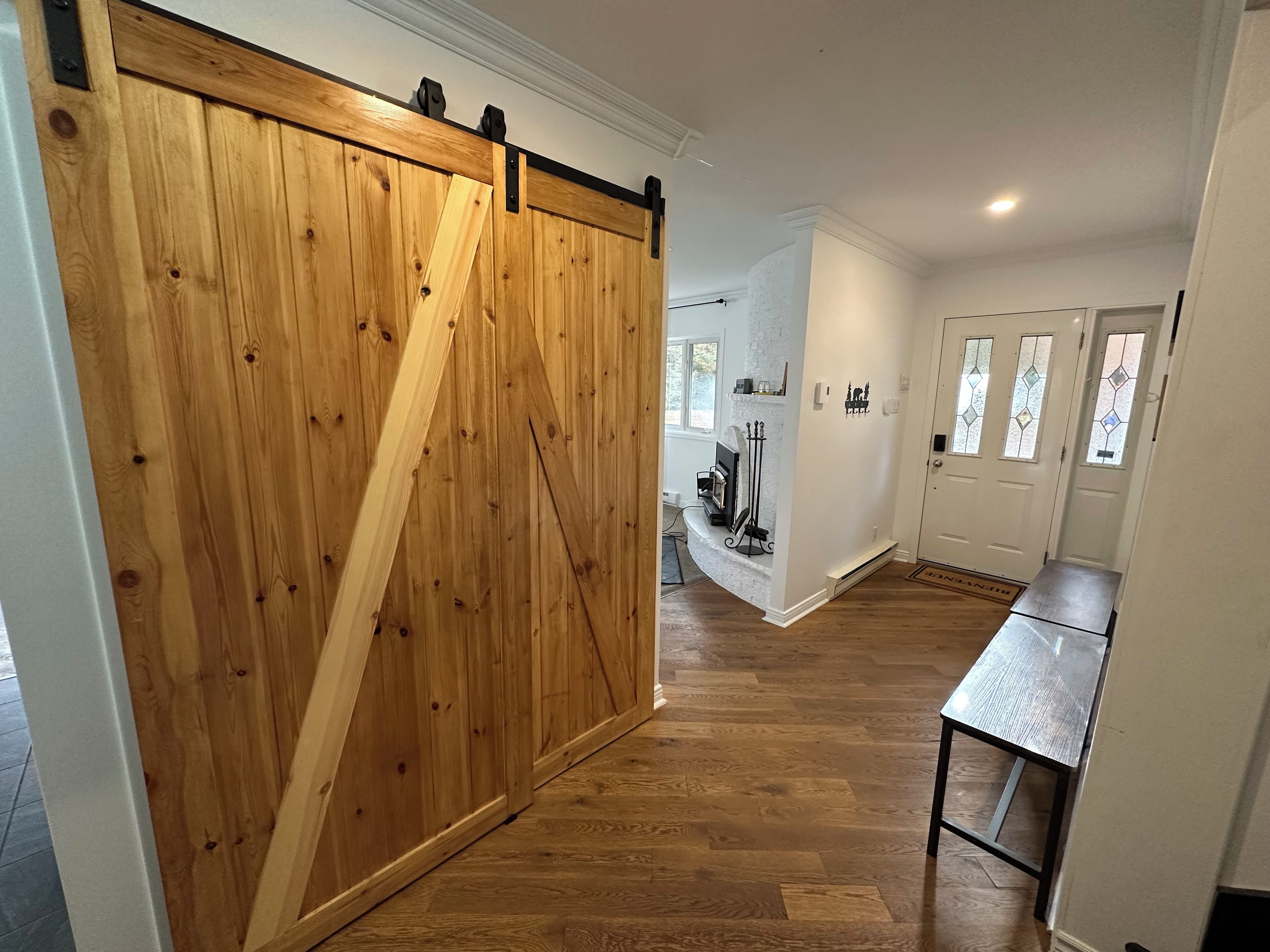 Een gang met een houten schuifdeur, een open haard en een eettafel.