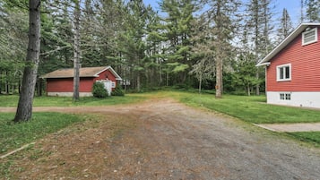 A gravel driveway leading to two red cabins surrounded by a forest.